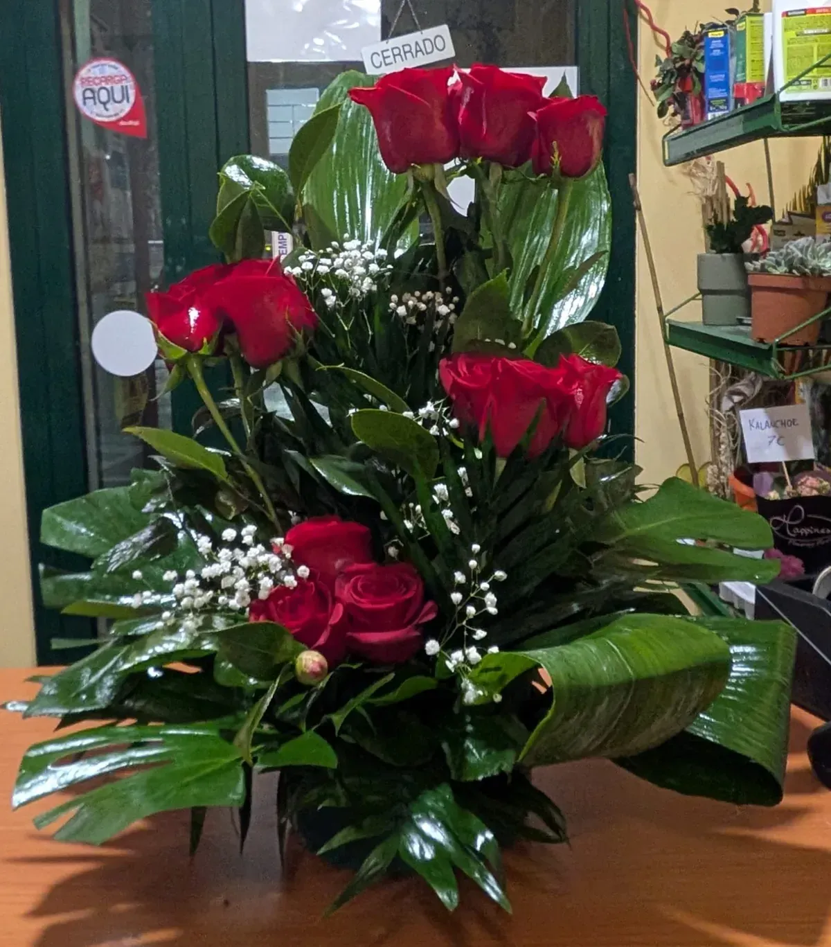 Ramo de flores rojas con hojas verdes brillantes en el escaparate de una tienda.