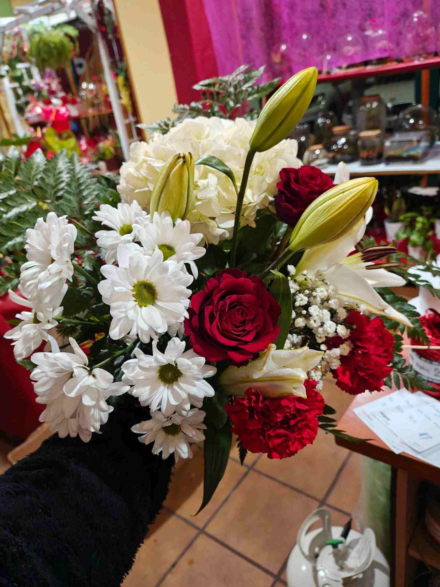 Ramo de margaritas blancas, rosas rojas y capullos de lirio en una floristería.
