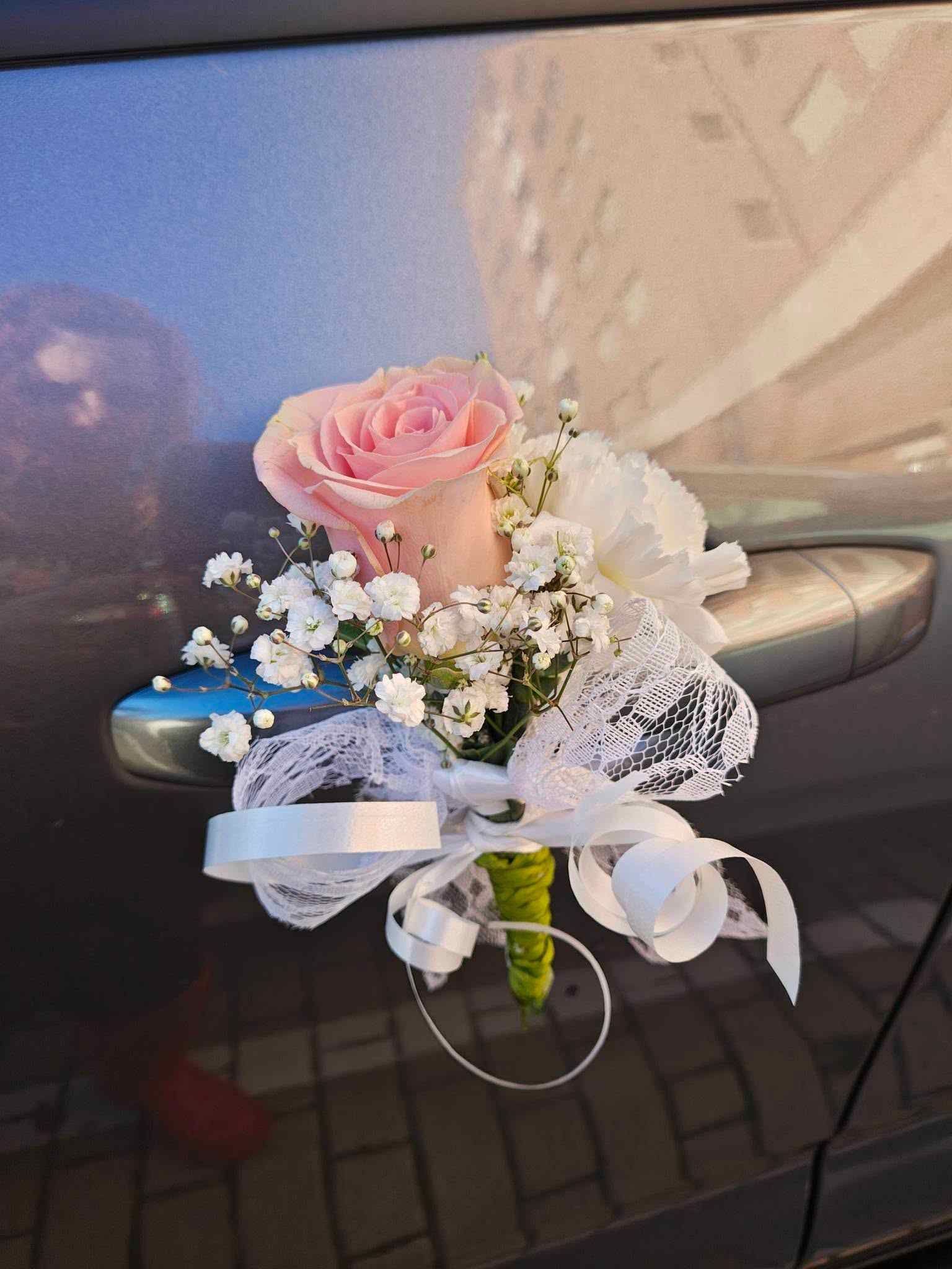 Pequeño ramo floral en tonos pastel con rosas rosas y flores blancas, envuelto en encaje blanco y cinta.