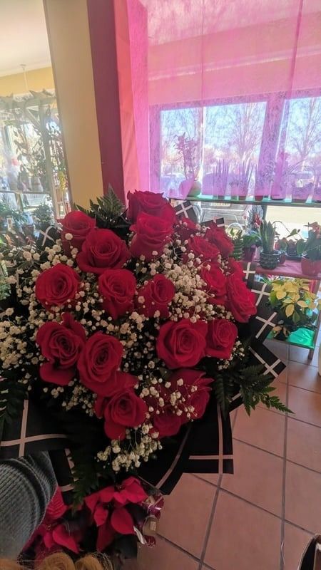 Gran ramo de rosas rojas y paniculata en una floristería cerca de una ventana.