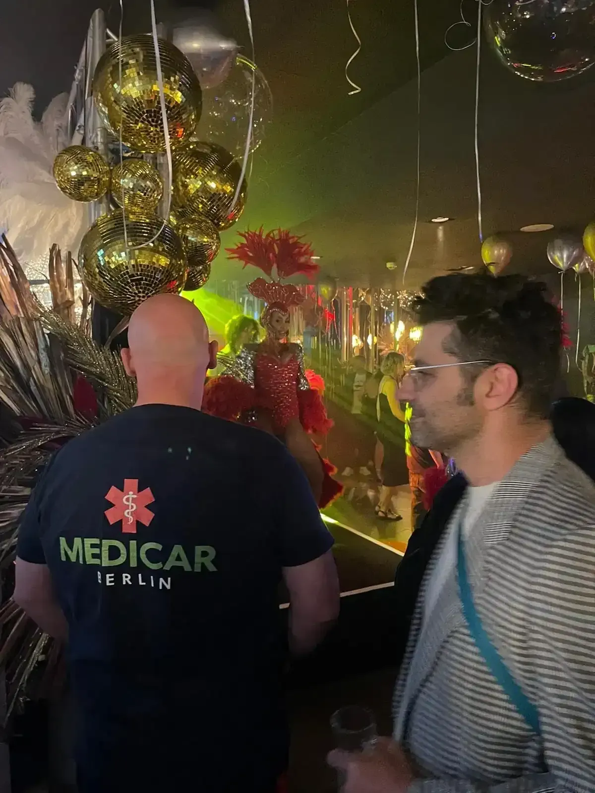 Ein Mann in einem Sanitäterhemd steht in einem überfüllten Raum