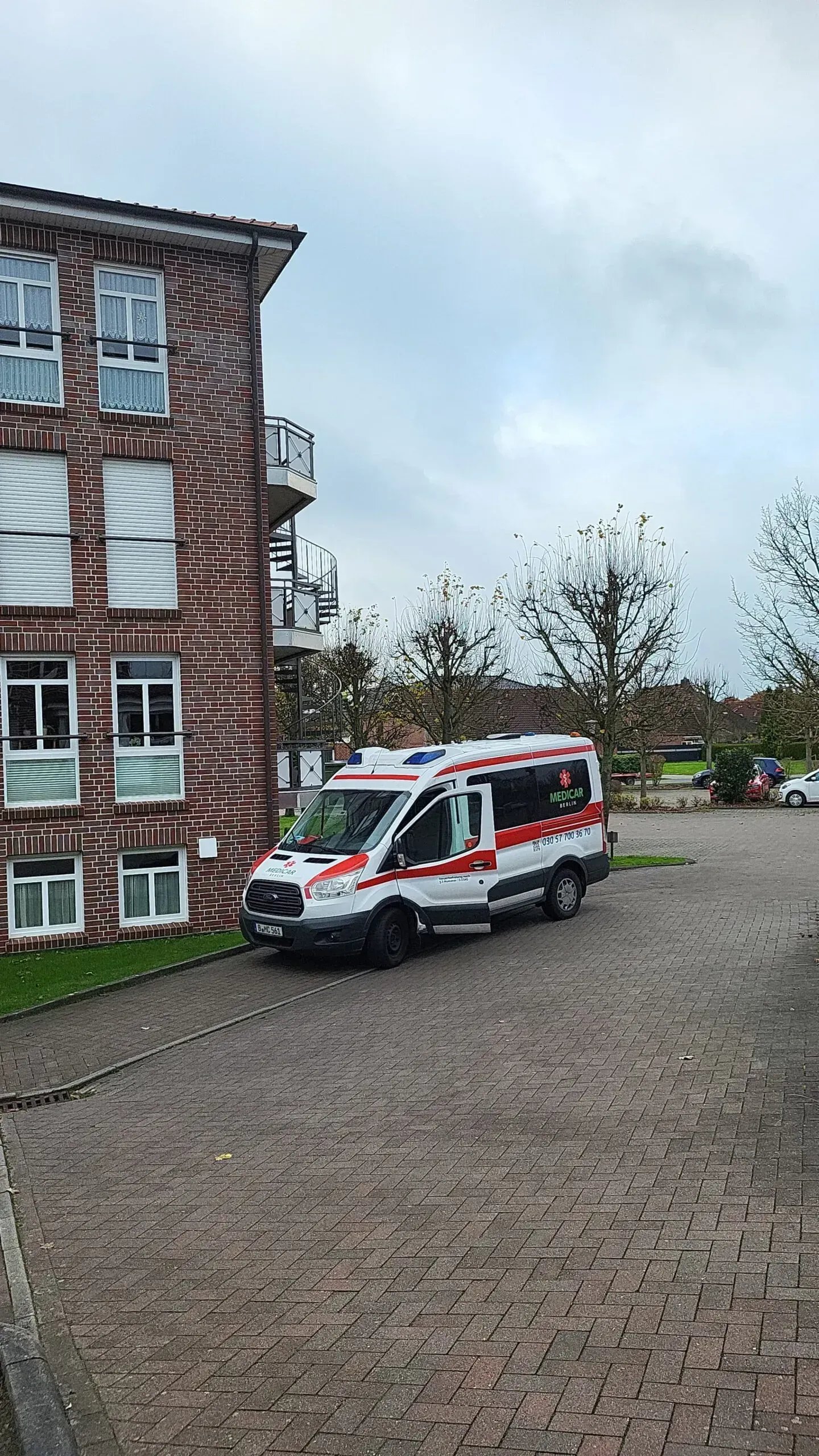 Vor einem Backsteingebäude parkt ein Krankenwagen.