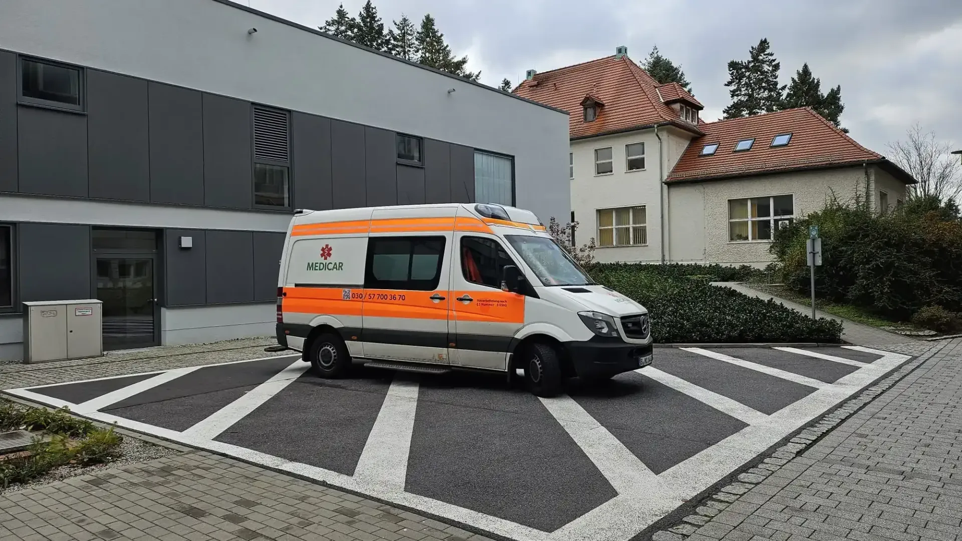 Auf einem Parkplatz vor einem Gebäude steht ein Krankenwagen.