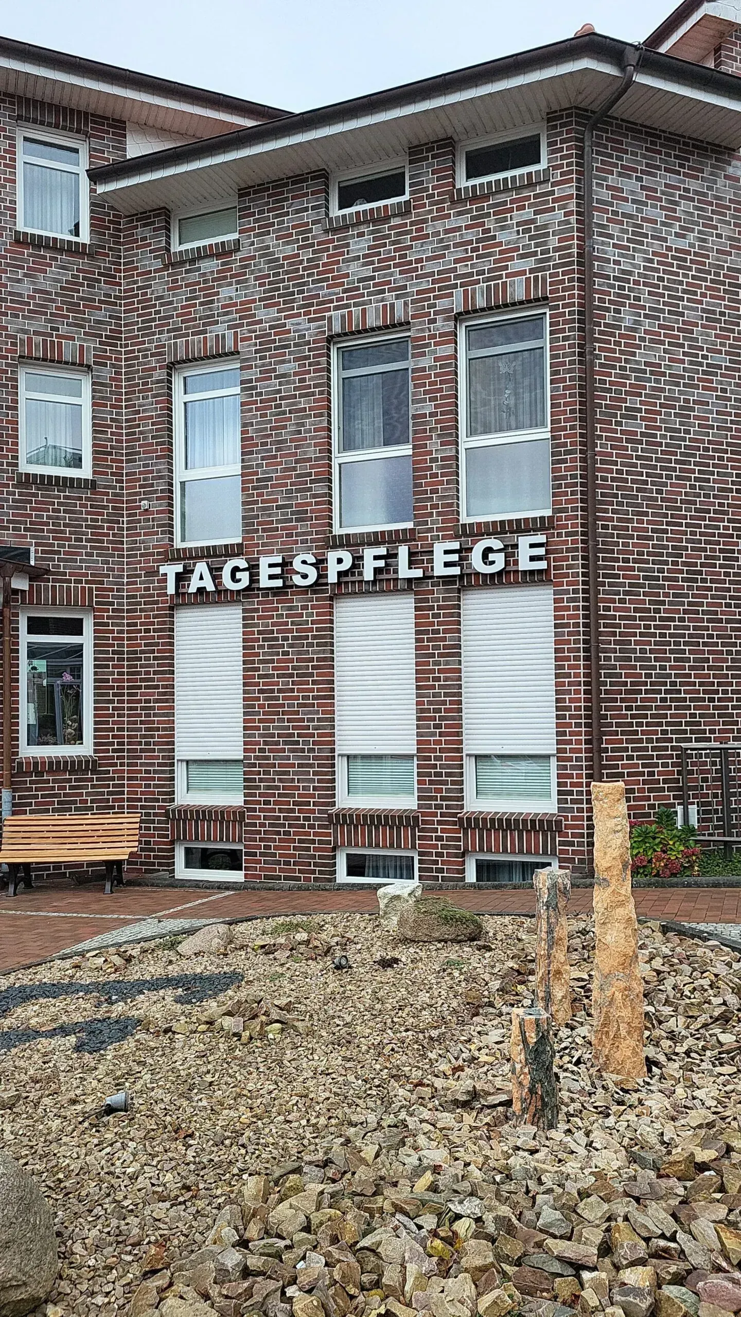 Ein großes Backsteingebäude mit einem Brunnen davor.