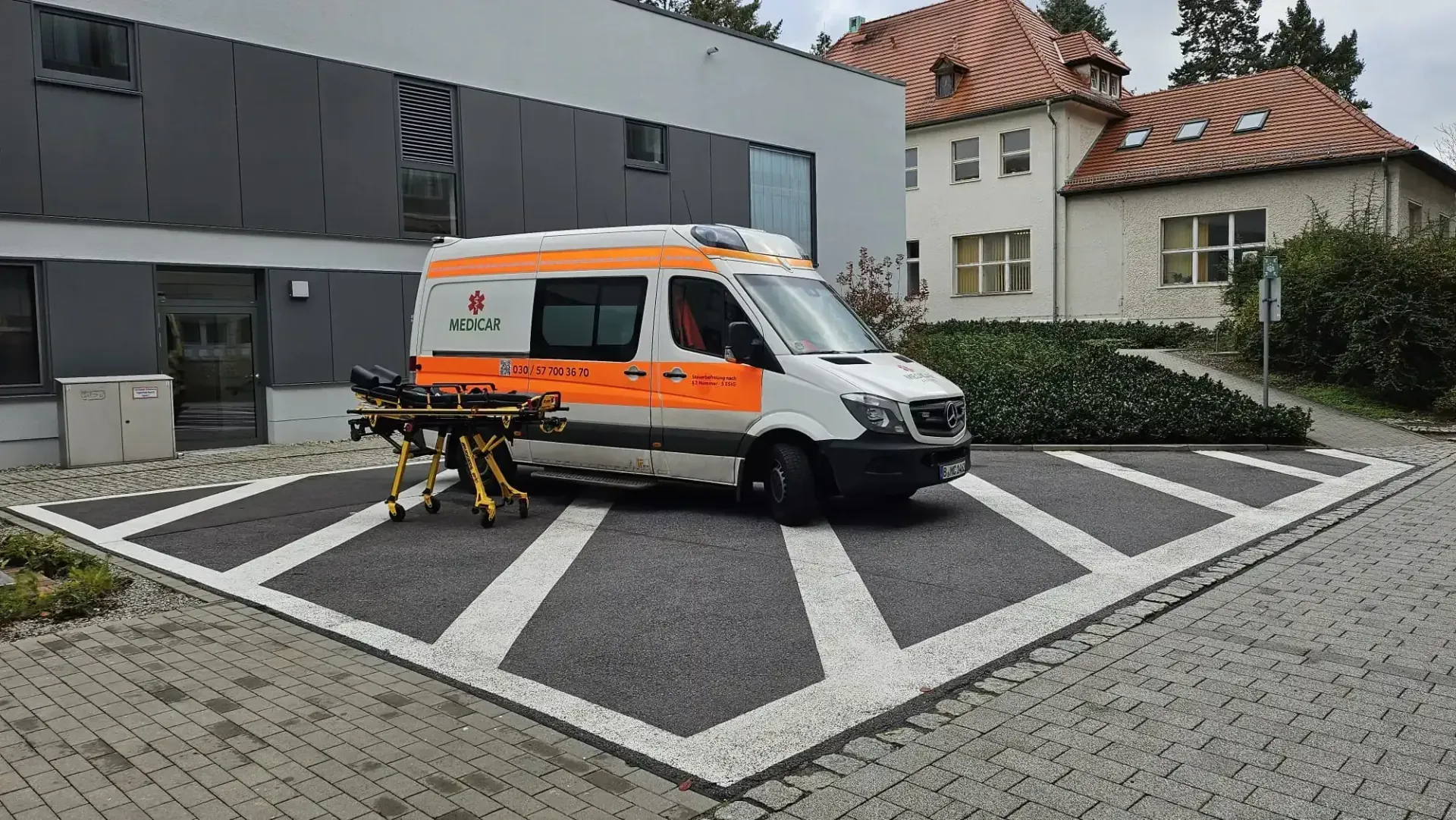 Auf einem Parkplatz vor einem Gebäude steht ein Krankenwagen.