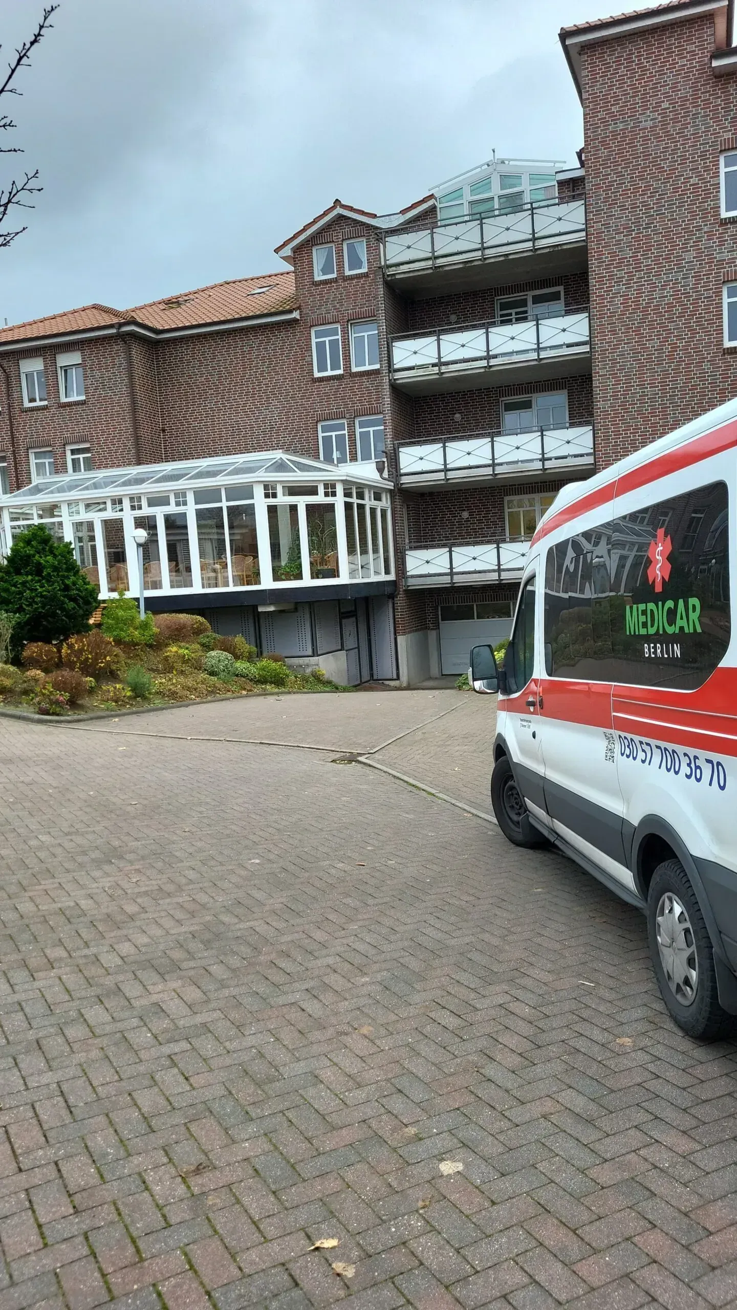 Vor einem Backsteingebäude parkt ein Krankenwagen.