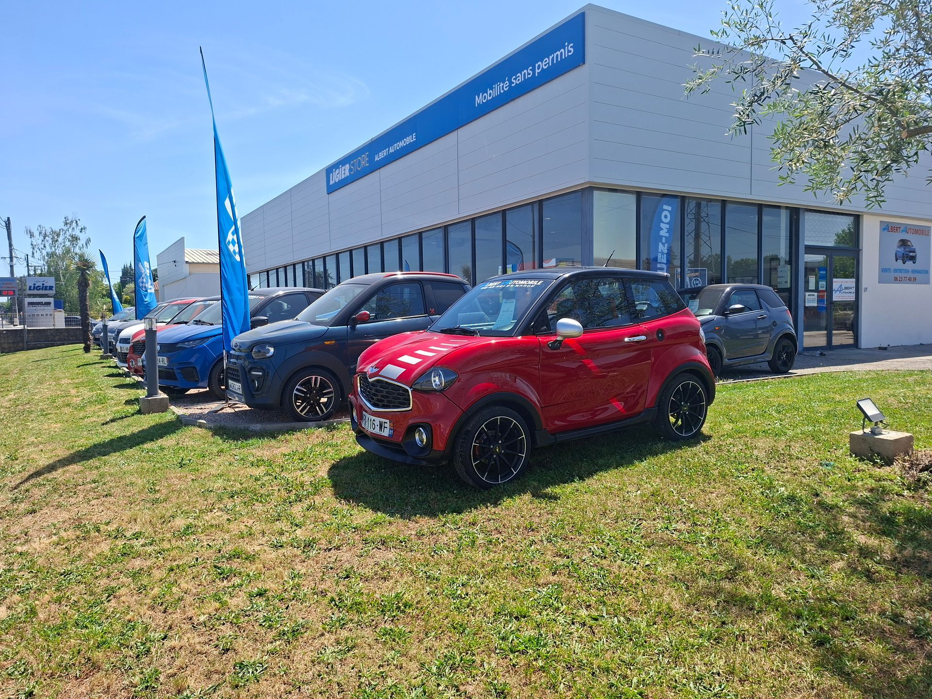 Voitures compactes garées devant une concession automobile.