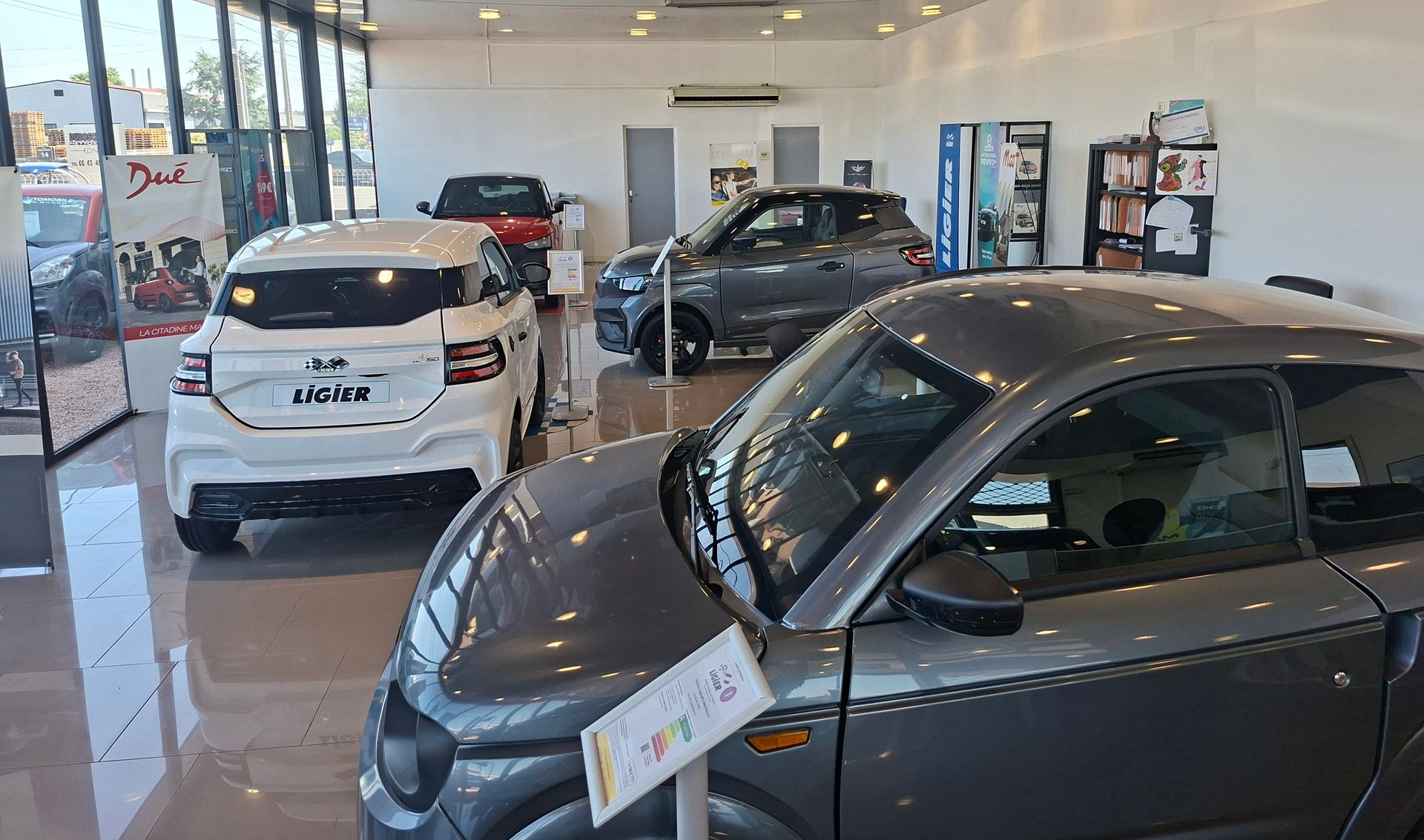 Salle d'exposition automobile avec quatre voitures présentées.