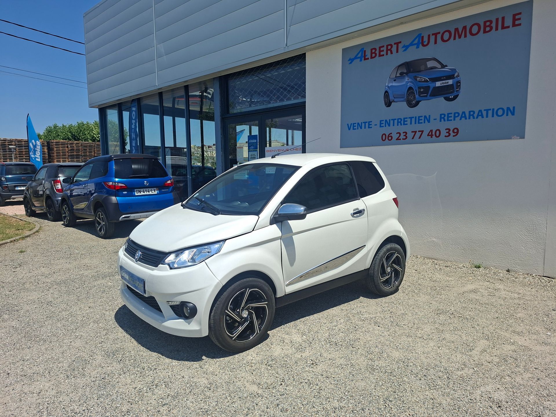 Voiture compacte garée devant un garage automobile avec une enseigne sur le mur