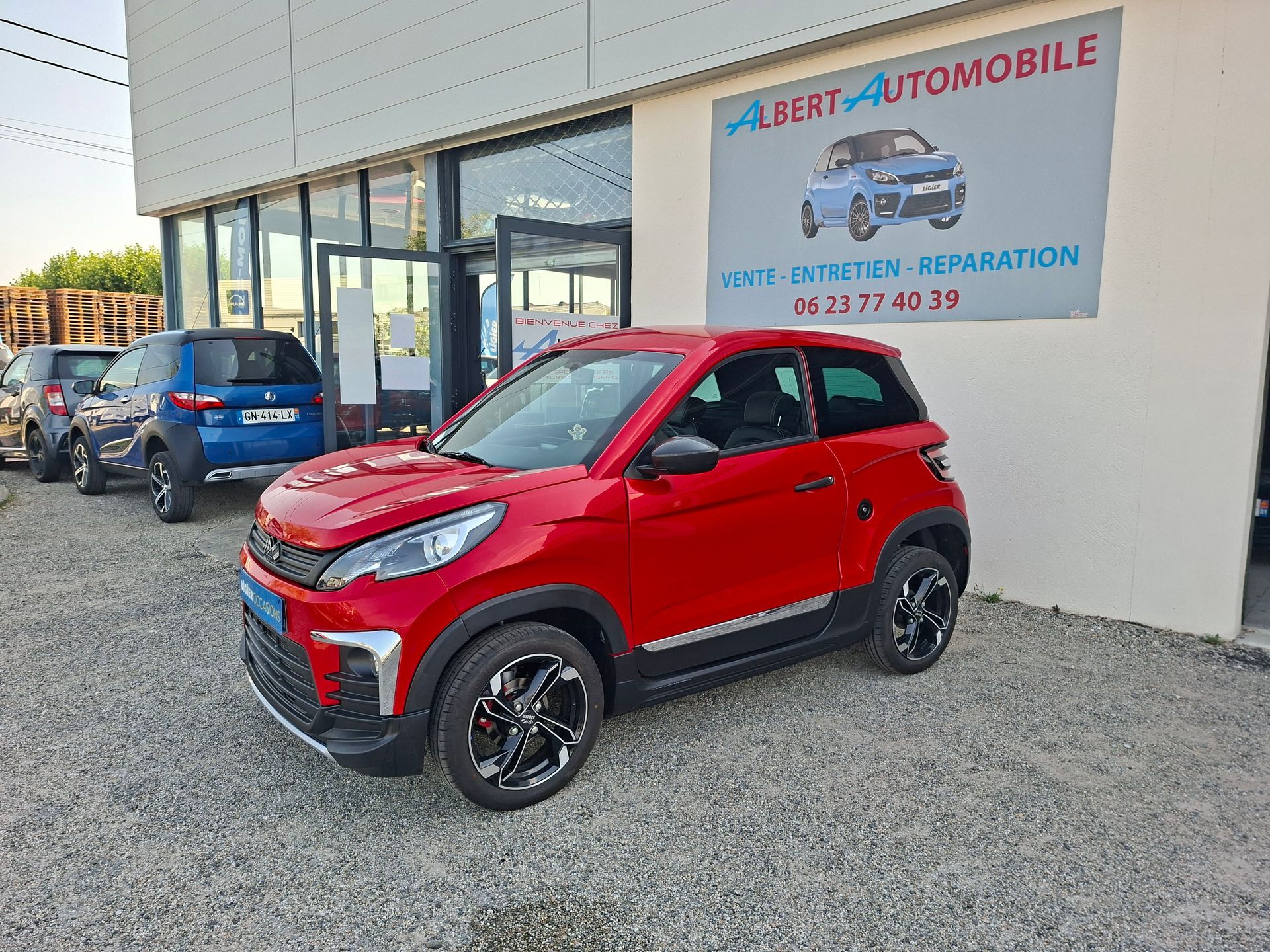 Voiture compacte garée devant un garage avec une enseigne Albert Automobile.
