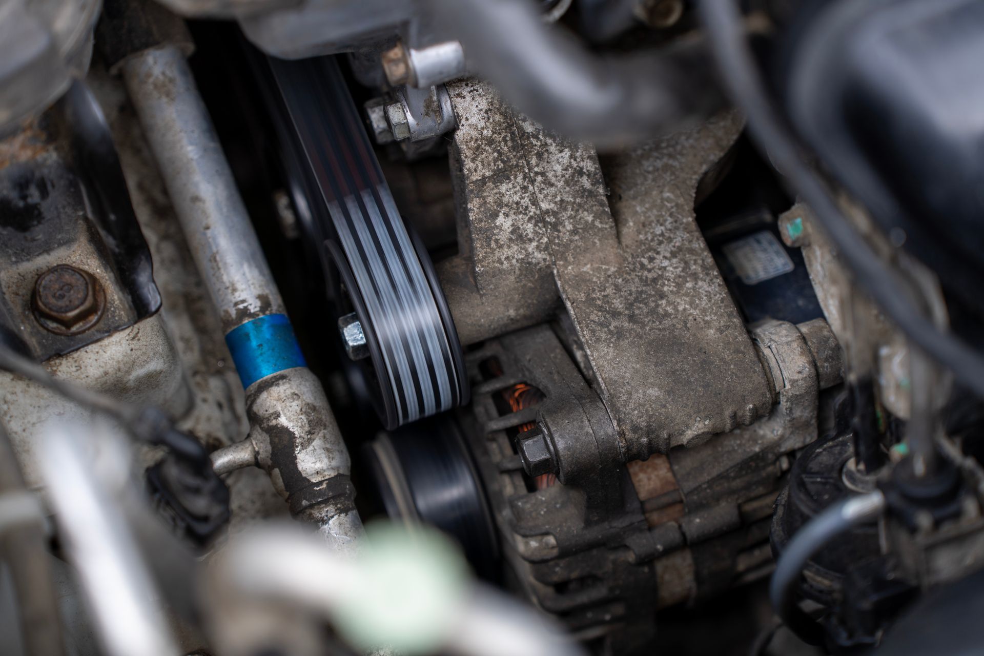 Gros plan sur un moteur de voiture avec une courroie serpentine et des composants d'alternateur.
