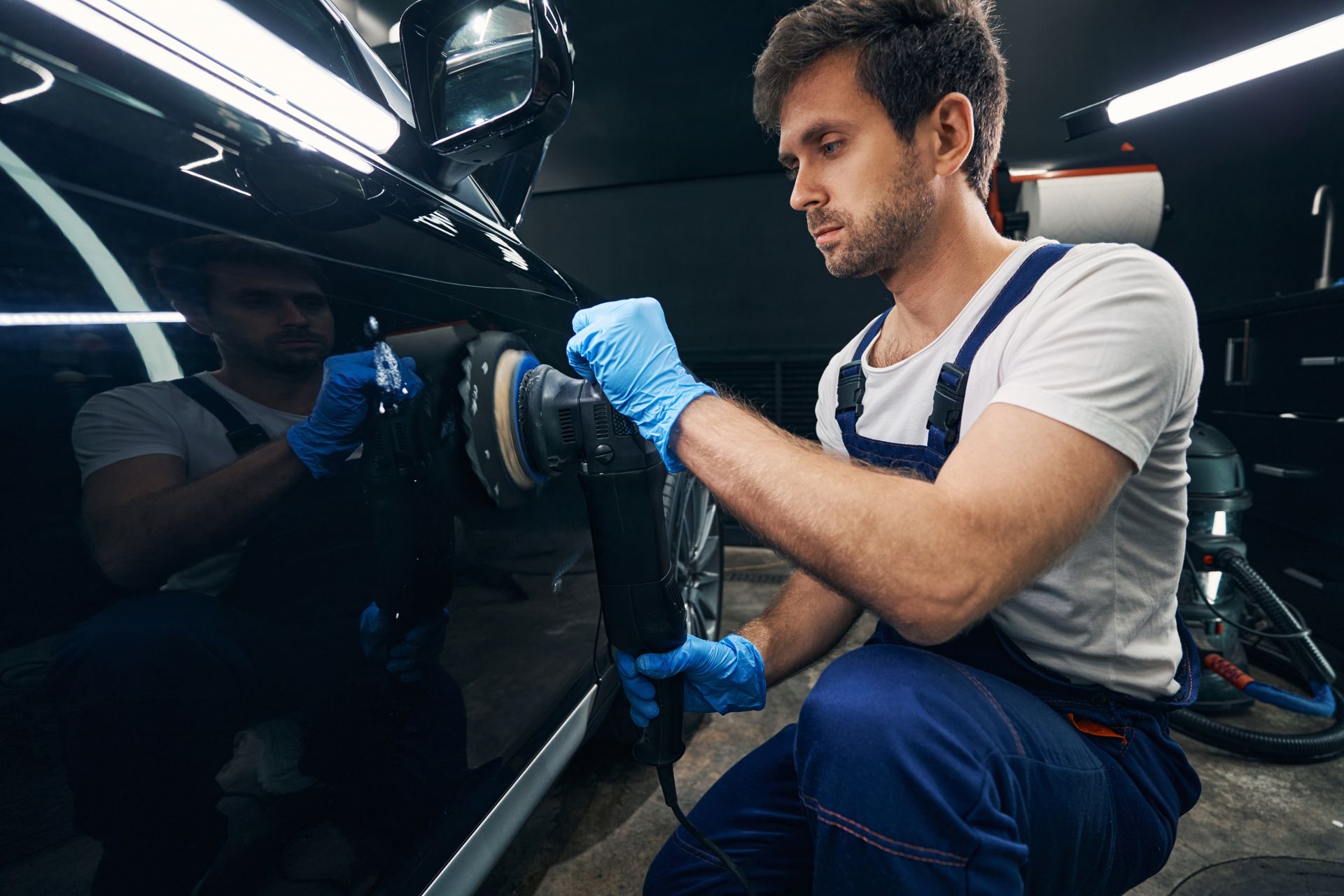 Un mécanicien polit une voiture dans un garage.