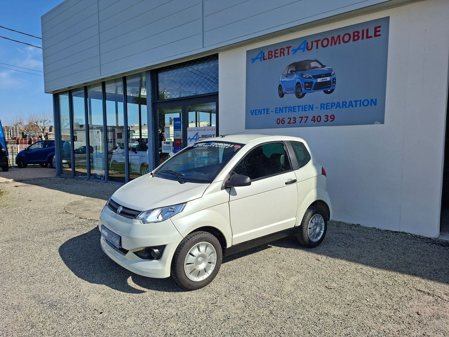 Voiture compacte garée devant une concession automobile.