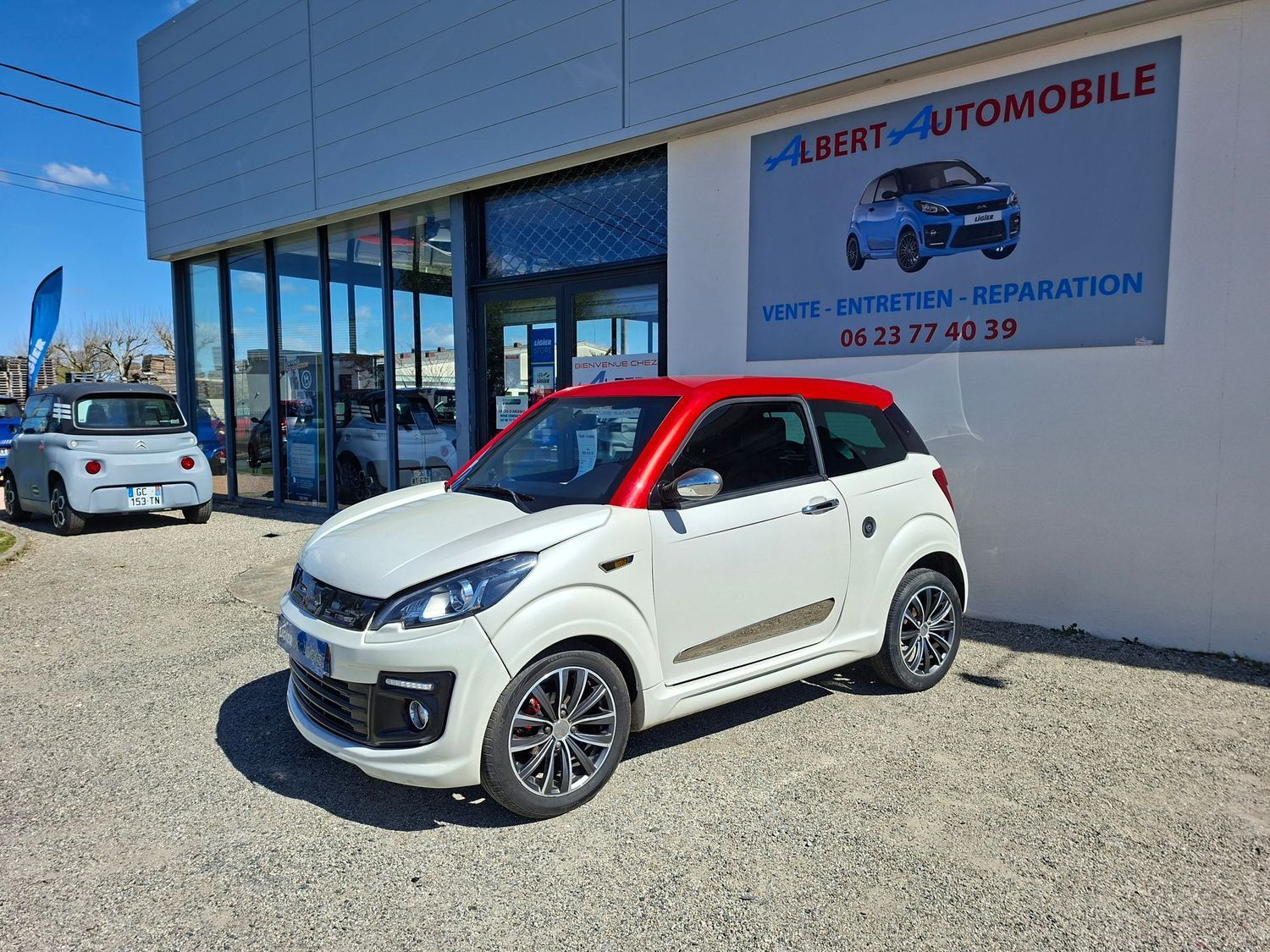 Voiture compacte garée devant une concession automobile.