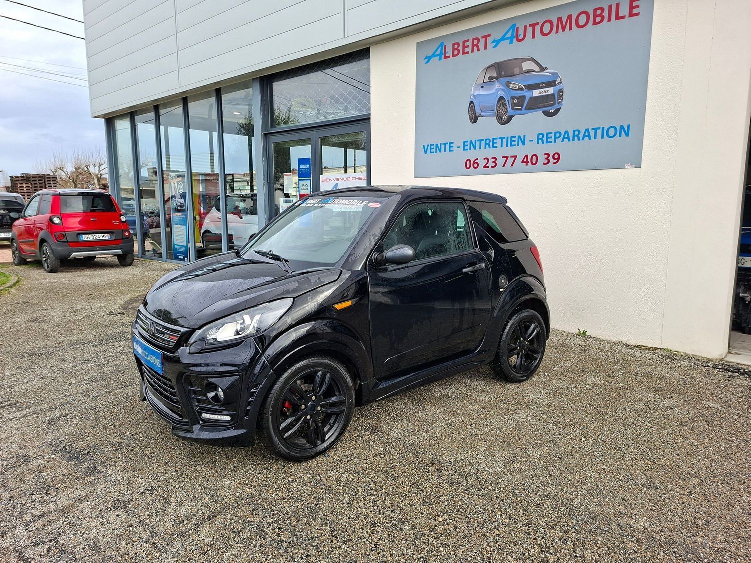 Voiture compacte garée devant un garage automobile avec une pancarte ALBERT AUTOMOBILE.
