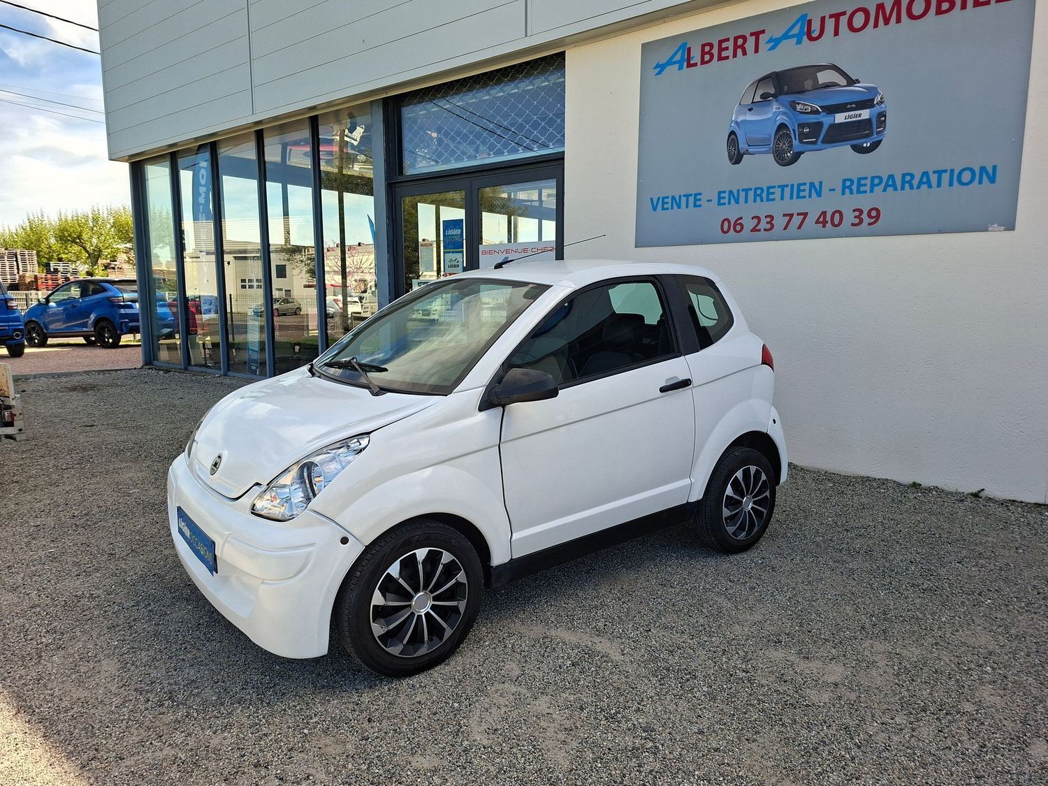 Voiture compacte garée devant un garage automobile.
