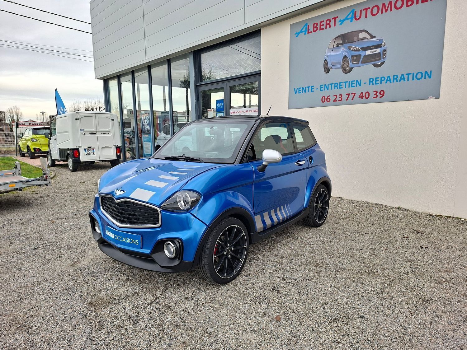 Voiture compacte garée devant un garage avec une enseigne Albert Automobile.