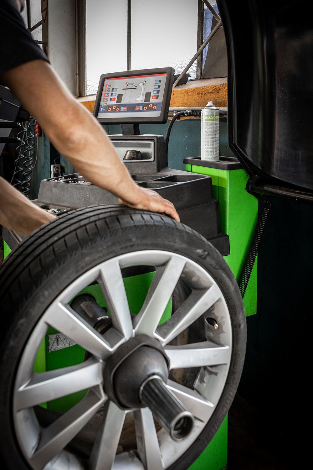 Eine Person wuchtet einen Reifen auf einer Maschine aus.