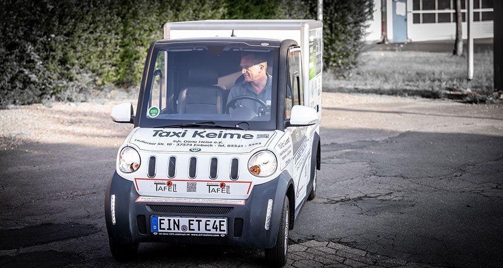 Ein Mann fährt einen kleinen Lastwagen mit einem Nummernschild, auf dem steht „ein ete4e“