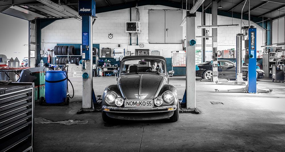 Ein Käfer steht auf einer Hebebühne in einer Garage.