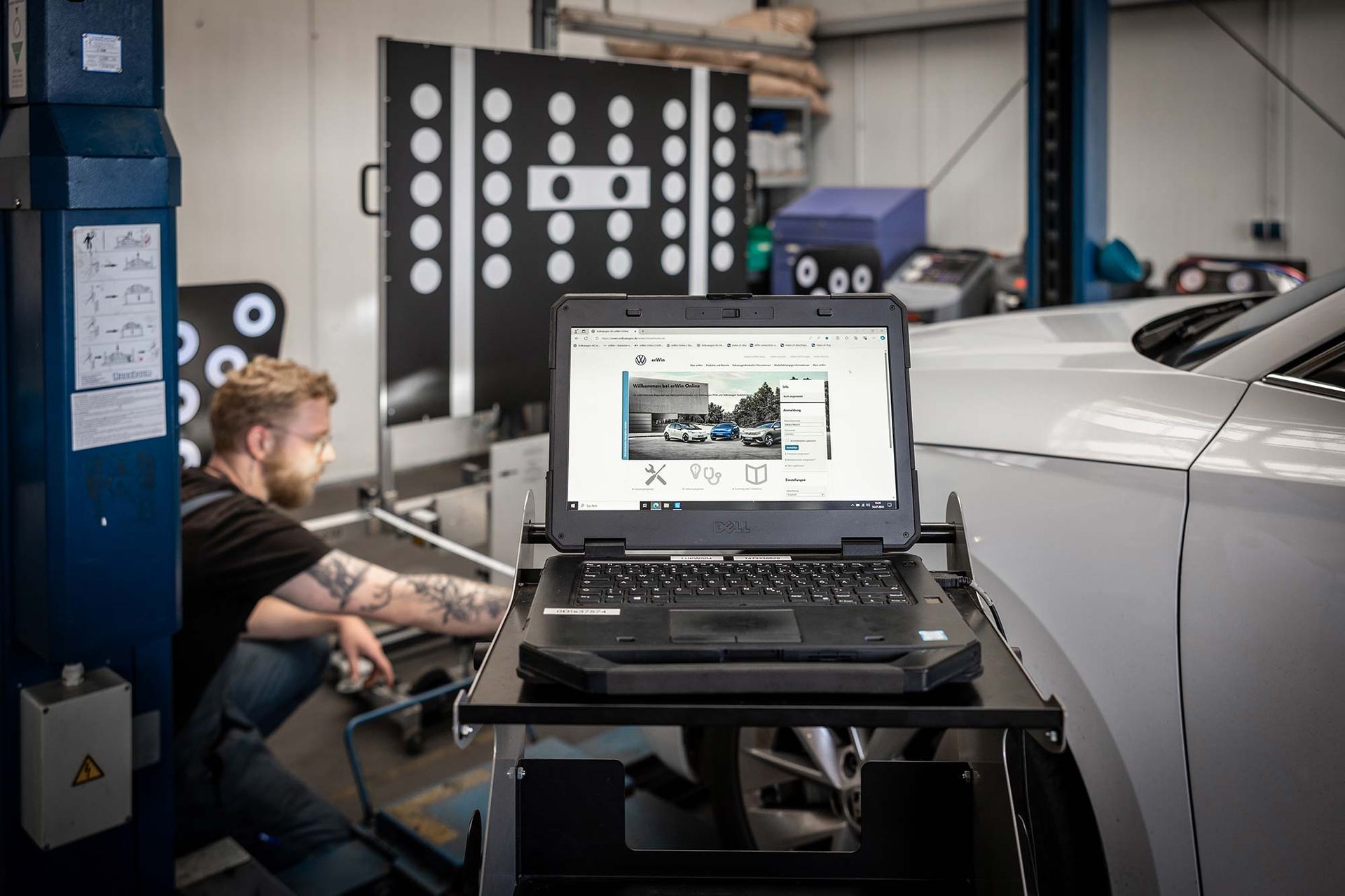 Ein Mann sitzt in einer Garage vor einem Laptop.
