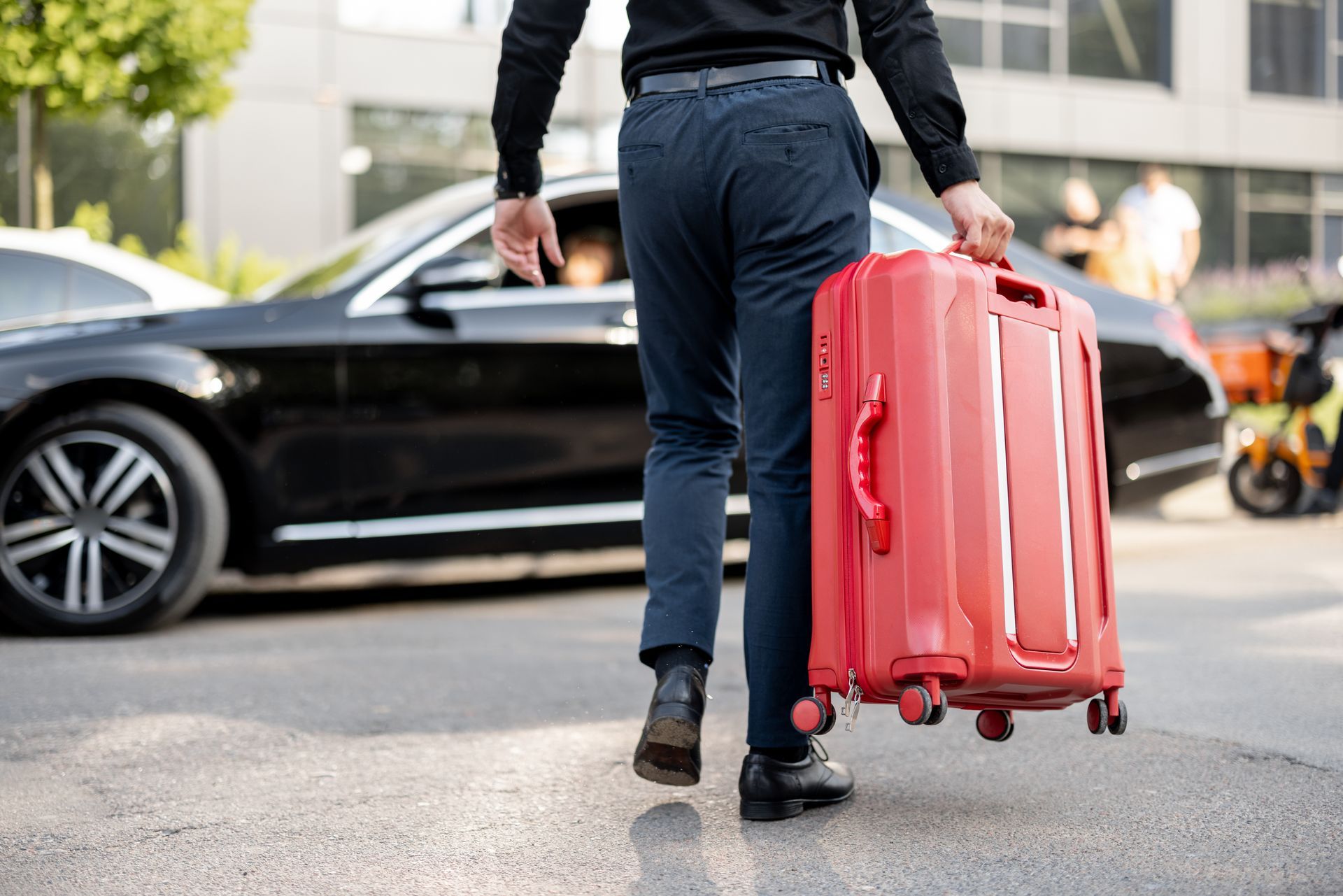 Chauffeur de taxi portant une valise rouge en direction du coffre d'un véhicule