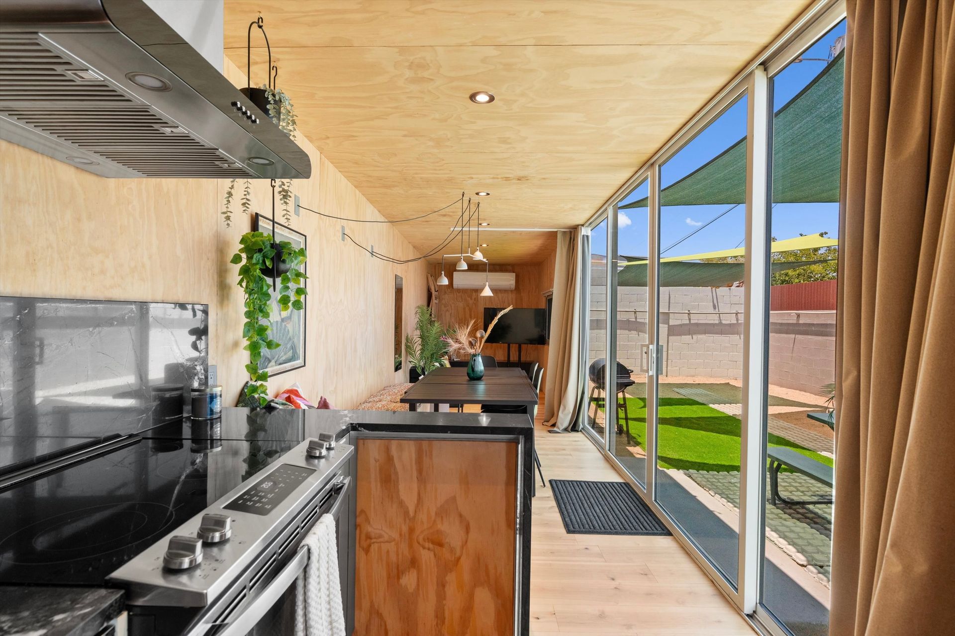 Kitchen with black countertops, wood cabinets, and a view of a yard through sliding glass doors.