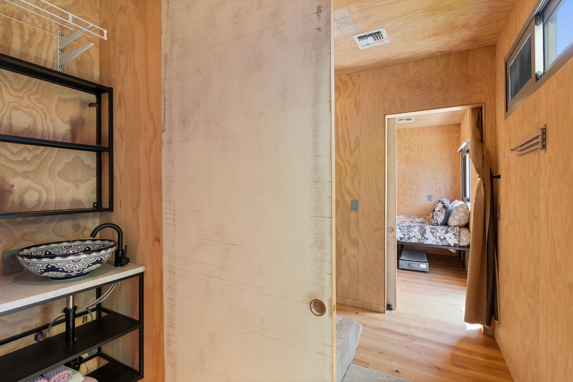 Interior of a modern home featuring a bathroom with a patterned sink and a doorway leading to a bedroom.