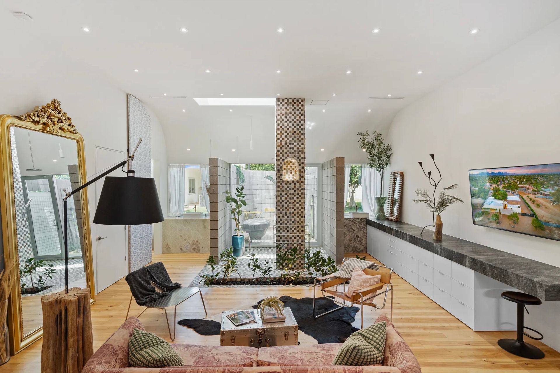 Spacious modern living room with a large mirror, pink couch, and open doors to a patio.