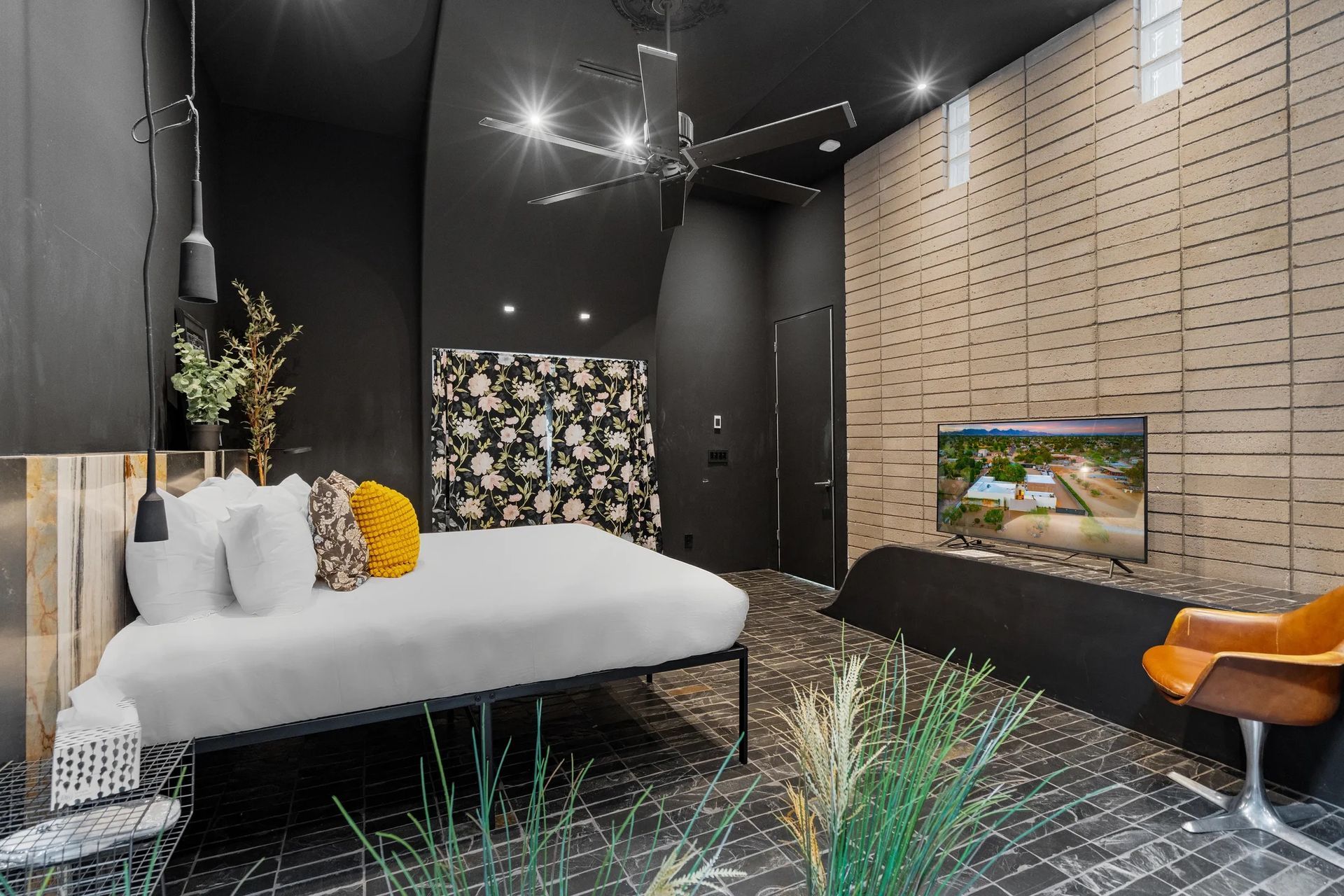 Modern bedroom with black walls, a white bed, and a textured wood accent wall with a TV.
