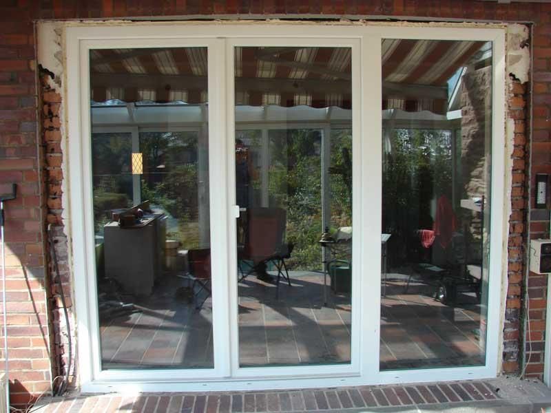 Eine weiße Glasschiebetür mit einer Ziegelwand dahinter