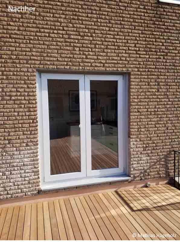 Ein Backsteingebäude mit einer weißen Tür und einem Holzdeck