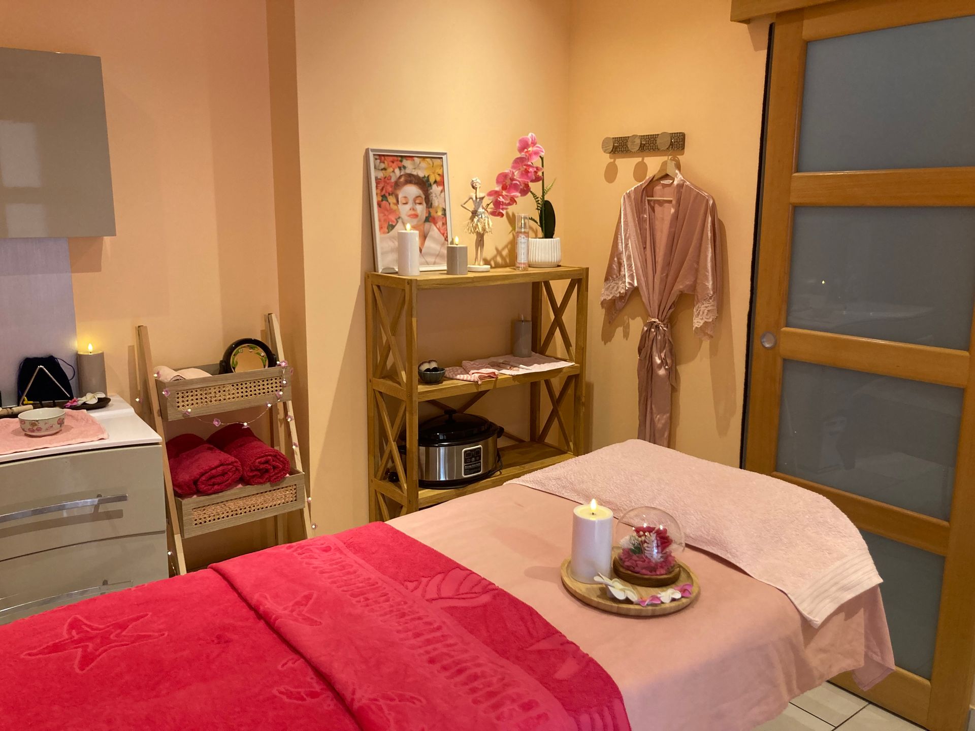 Chambre confortable avec couvre-lit, commode, étagères et peignoir accroché près de la porte.