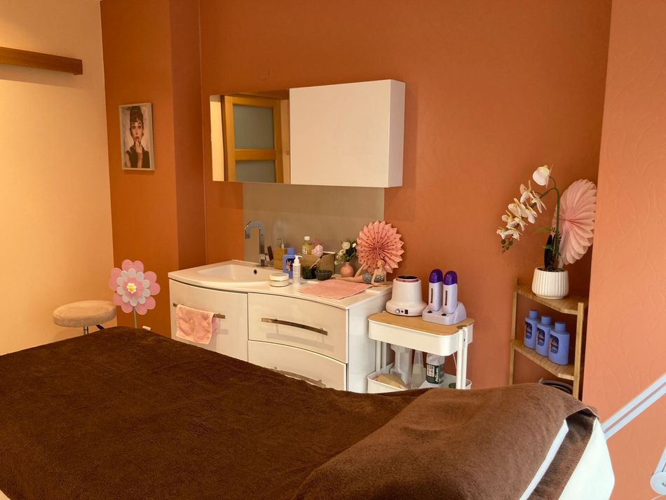 Petite chambre avec une commode, un miroir, des fleurs et un lit.