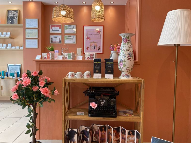 Intérieur chaleureux de boutique avec étagères en bois, lampes suspendues, fleurs et tableaux.