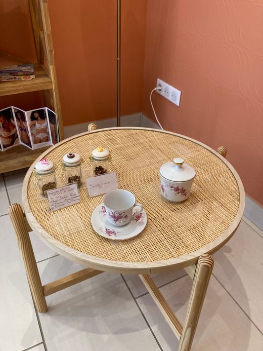 Petite table ronde en osier avec un service à thé et des bougies dans un coin, contre un mur.