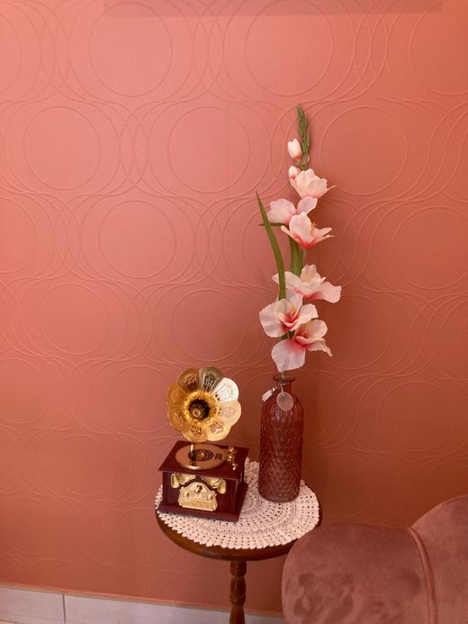 Petite table d'appoint avec un gramophone vintage, un vase rempli de fleurs et une boîte décorative, le tout adossé à un mur.