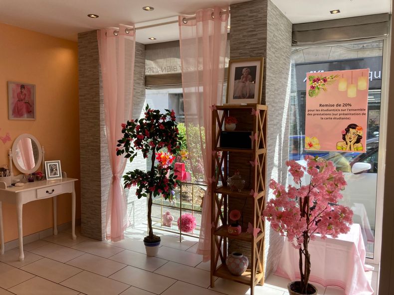 Intérieur de boutique florale avec sol carrelé, étagères d'exposition et affiche en vitrine.