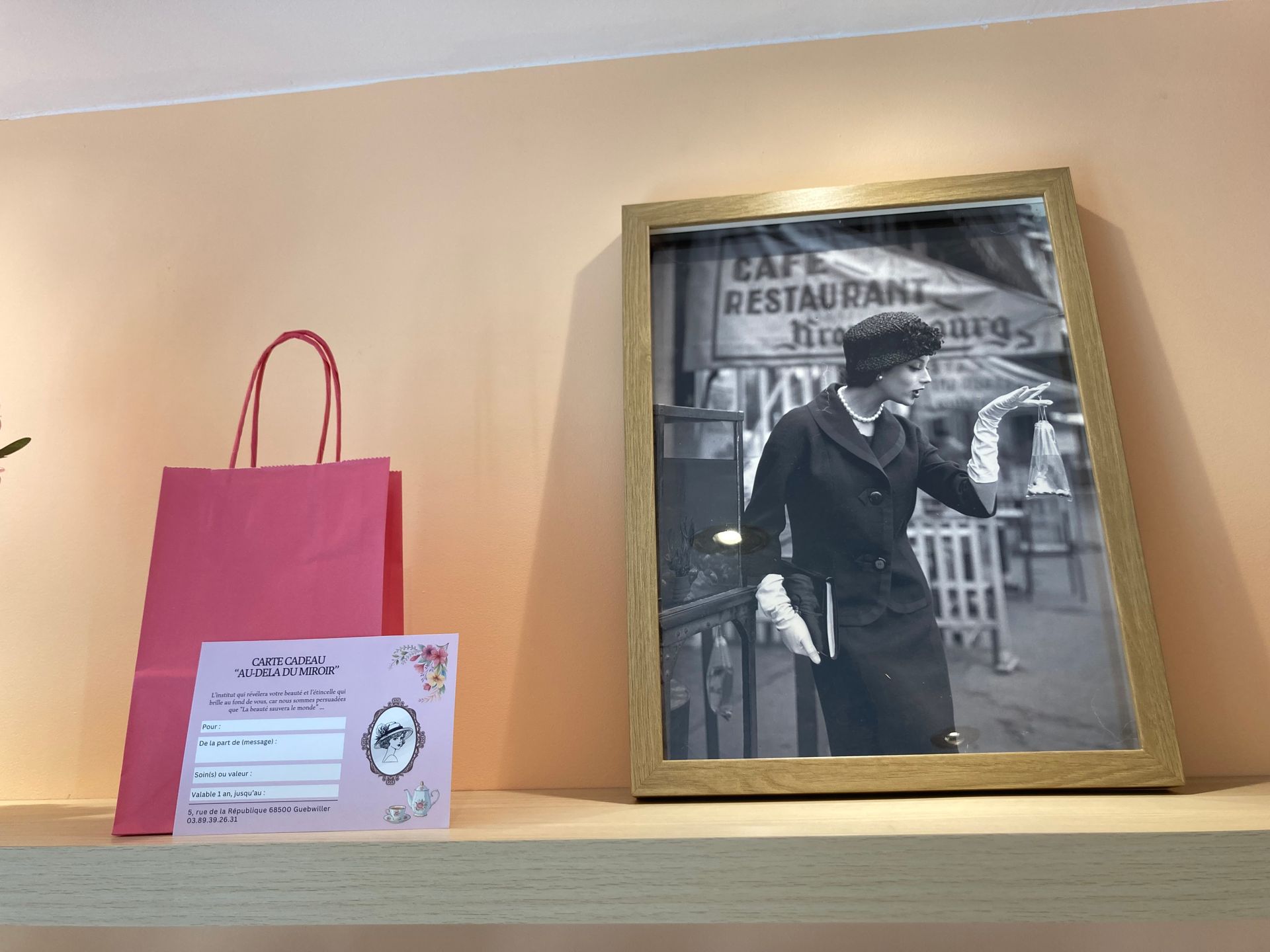 Un sac cadeau à côté d'une photo encadrée d'un institut, sur une étagère.