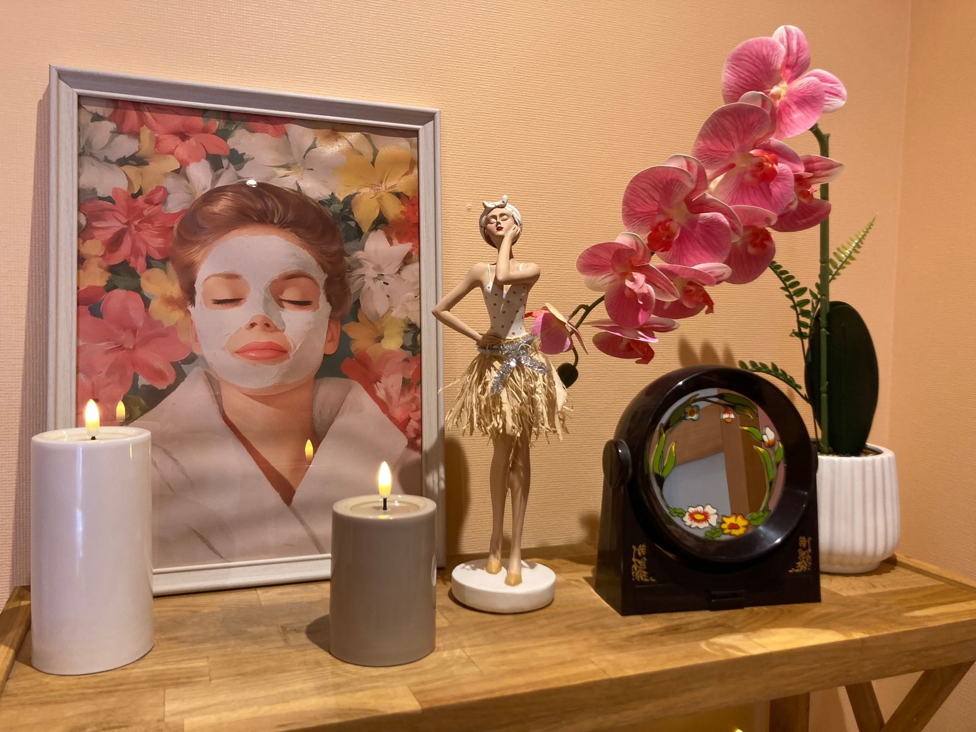 Un portrait encadré, des orchidées, des bougies et une figurine sur une étagère.