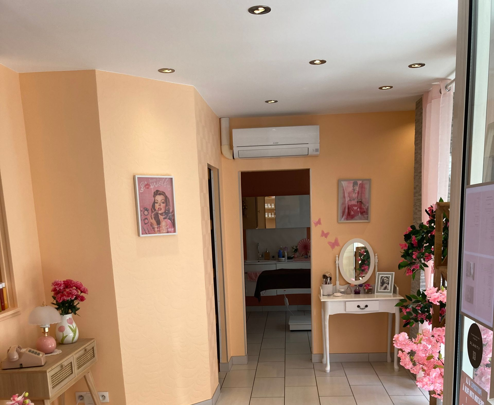 Couloir lumineux avec murs couleur, spots encastrés, tableaux encadrés, coiffeuse et fleurs.