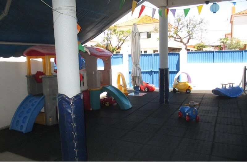 Parque infantil coberto com toldo, com estruturas de brincar e brinquedos coloridos.
