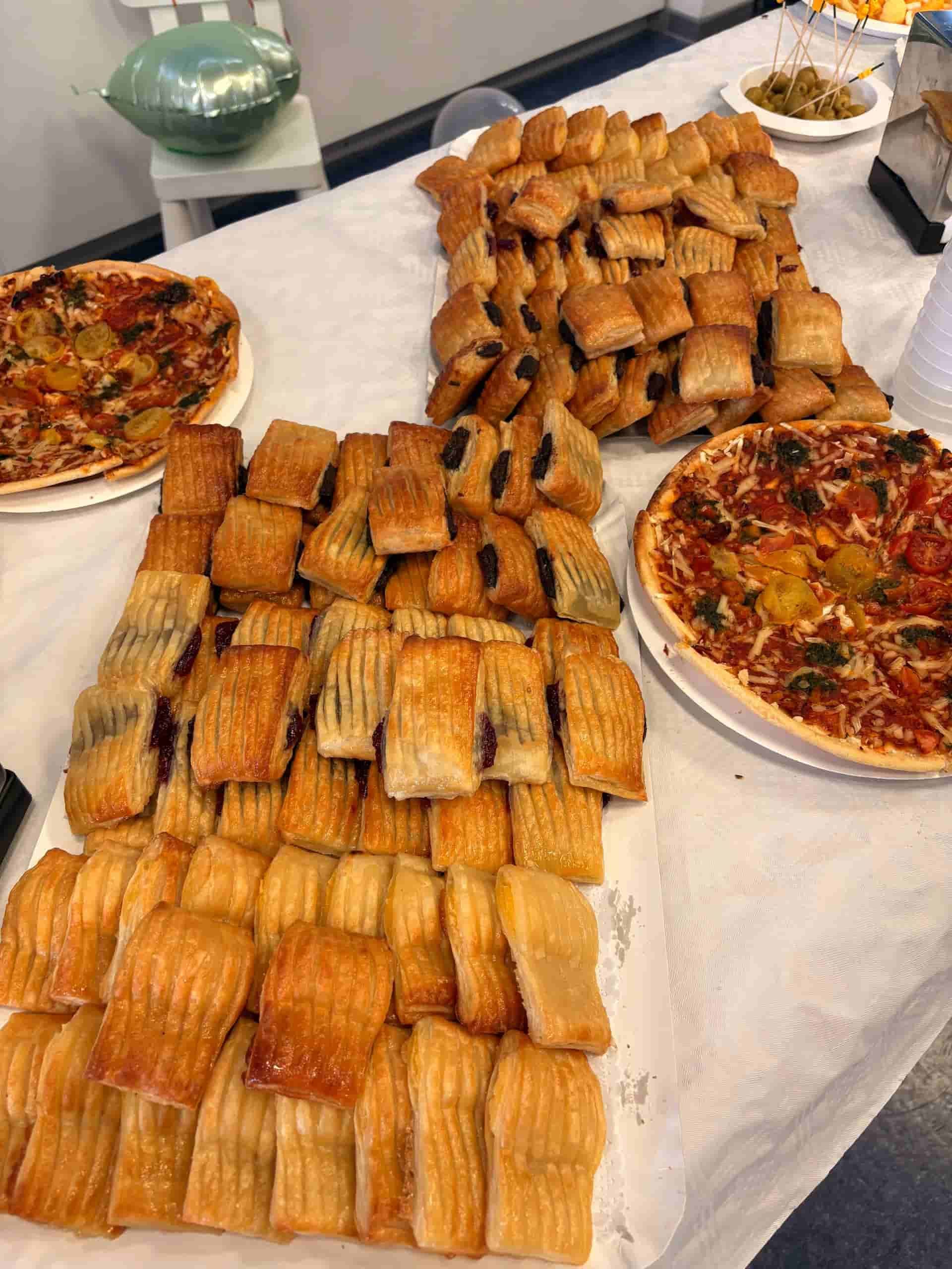 Buffet con pizzas y filas de pasteles.