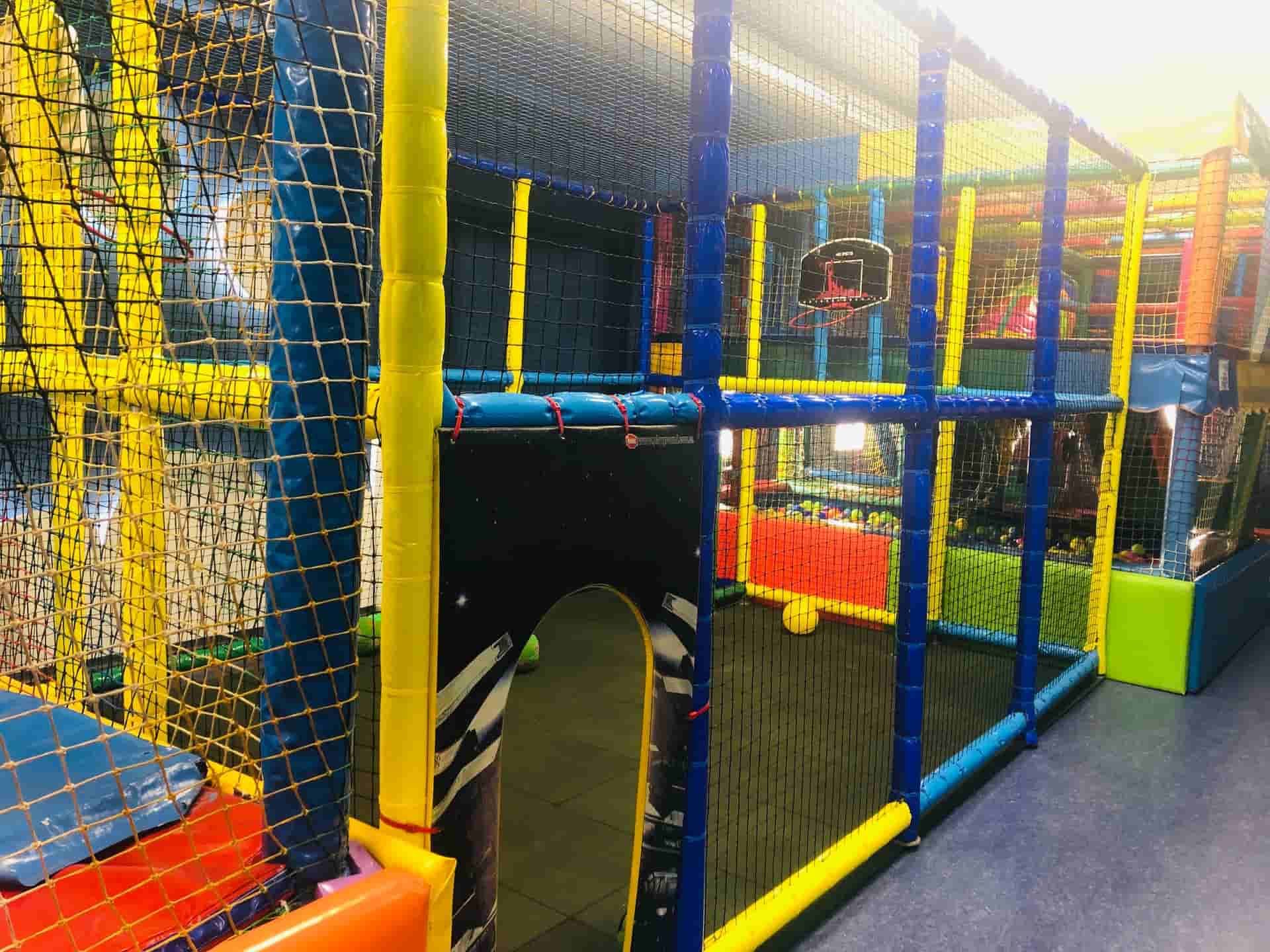 Parque infantil con túneles, redes y aro de baloncesto, con estructuras de color azul, amarillo y rojo.