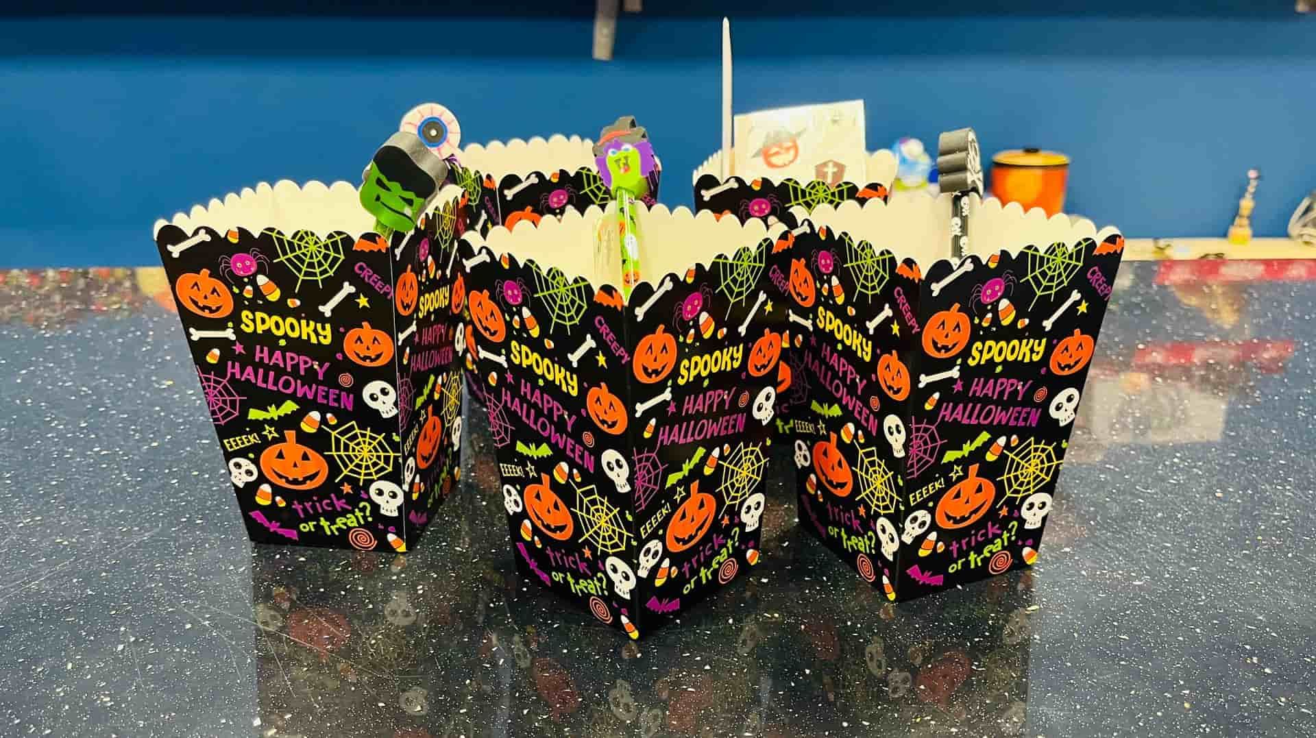 Cajas de palomitas de maíz de Halloween con diseños espeluznantes sobre una superficie brillante.