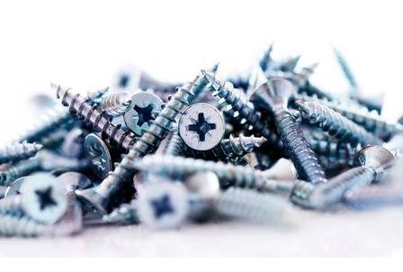 Una pila de tornillos sobre una superficie blanca.