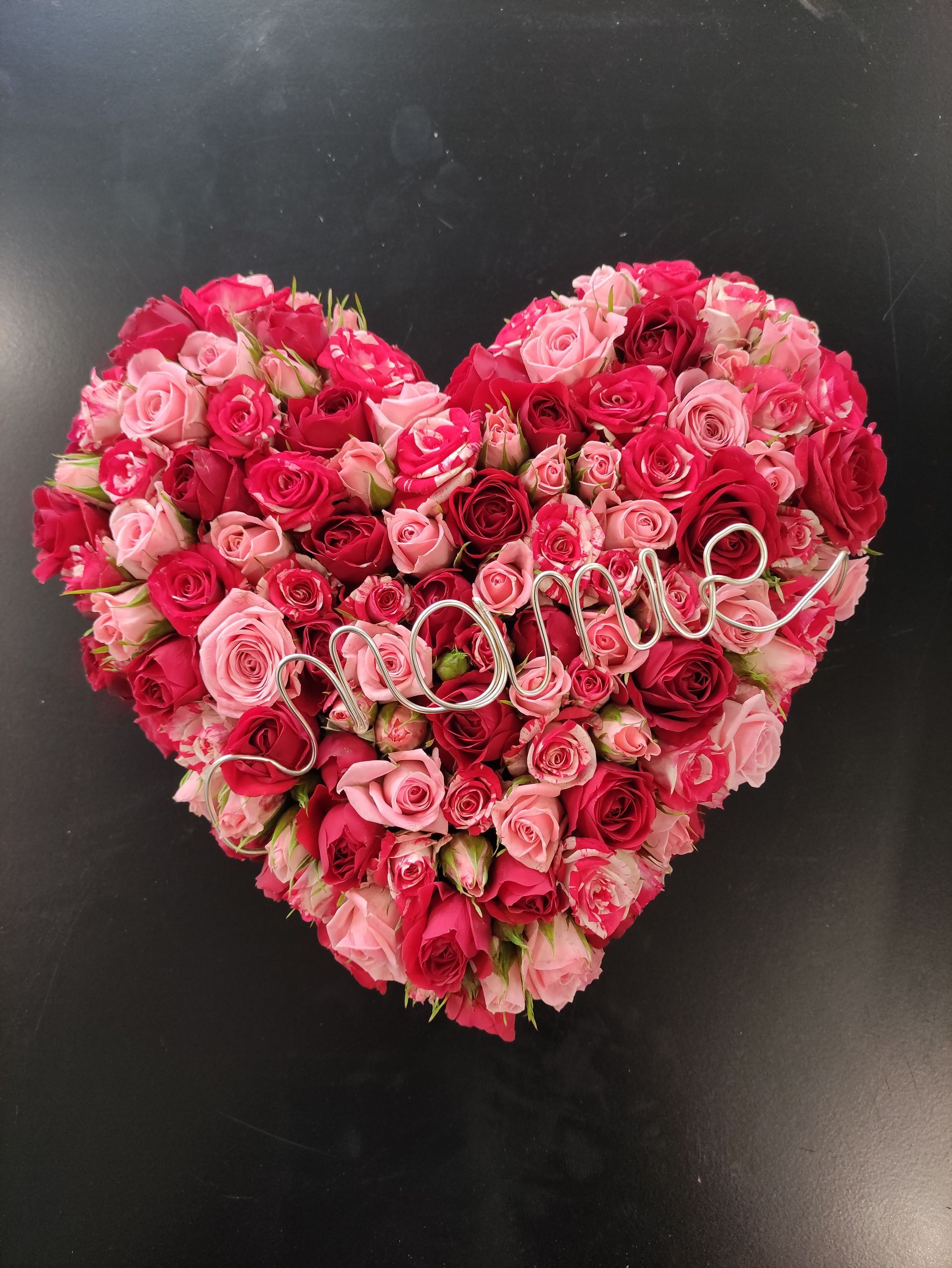 Un coeur avec des fleurs roses et rouges.