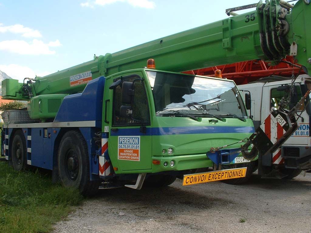 Camion-grue vert à flèche déployée, stationné à l'extérieur sur l'herbe
