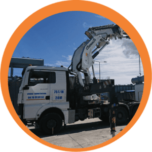 Camion-grue blanc à bras déployé, stationné à l'extérieur sous un ciel bleu
