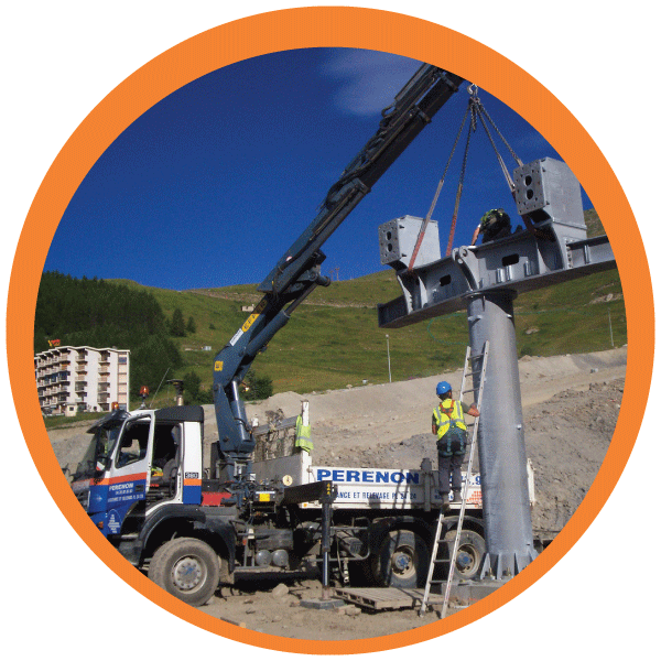 Camion-grue soulevant une structure métallique sur un chantier de construction, avec des ouvriers en équipement de sécurité à proximité.